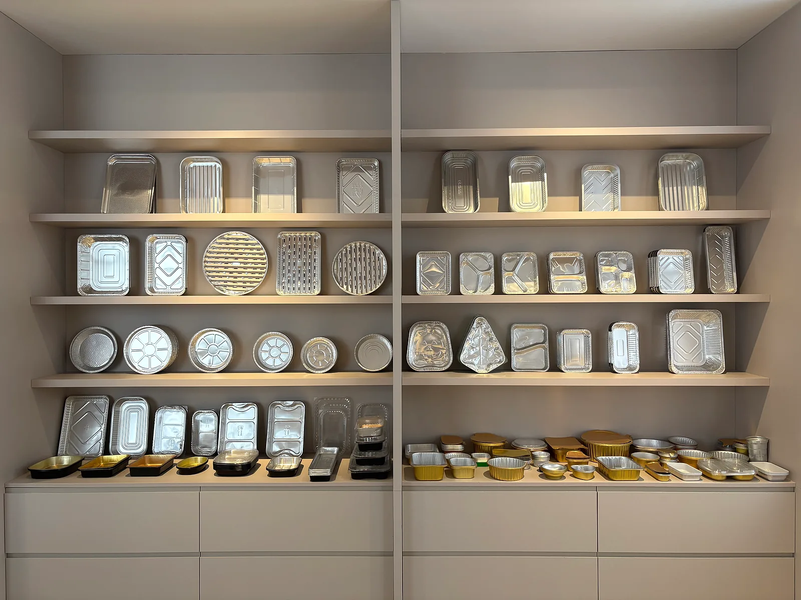 Gold and silver aluminum foil tray samples displayed in a showroom